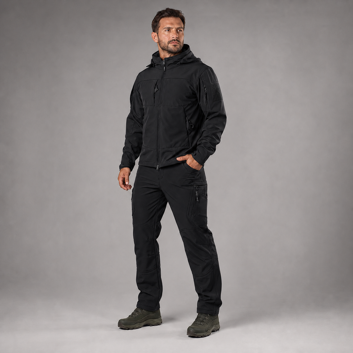 Man wearing black softshell jacket and utility trousers, full-body three-quarter studio view
